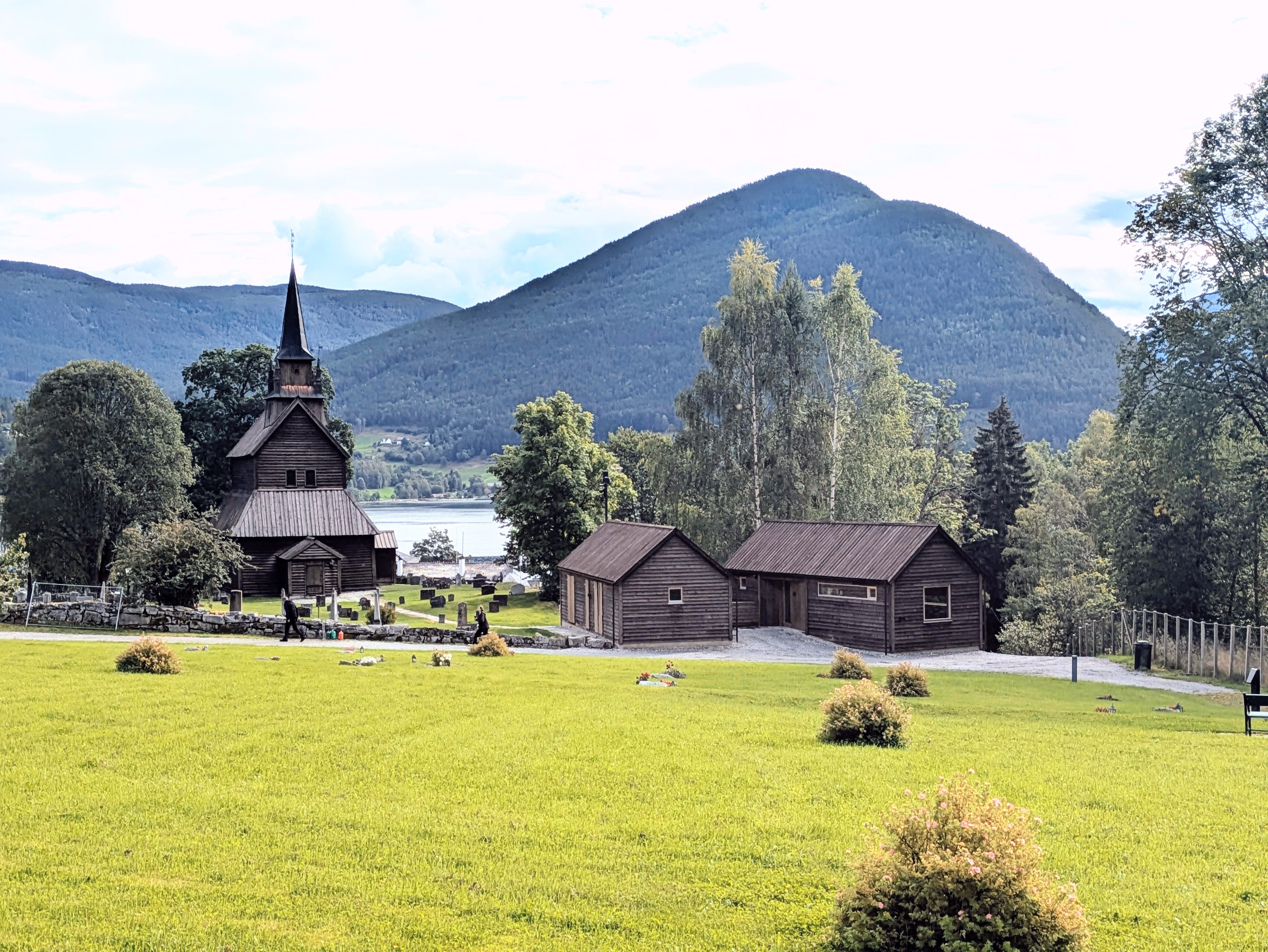 Foto av Kaupanger kyrkjegard med Kaupanger stavkyrkje og den nye kyrkjestova